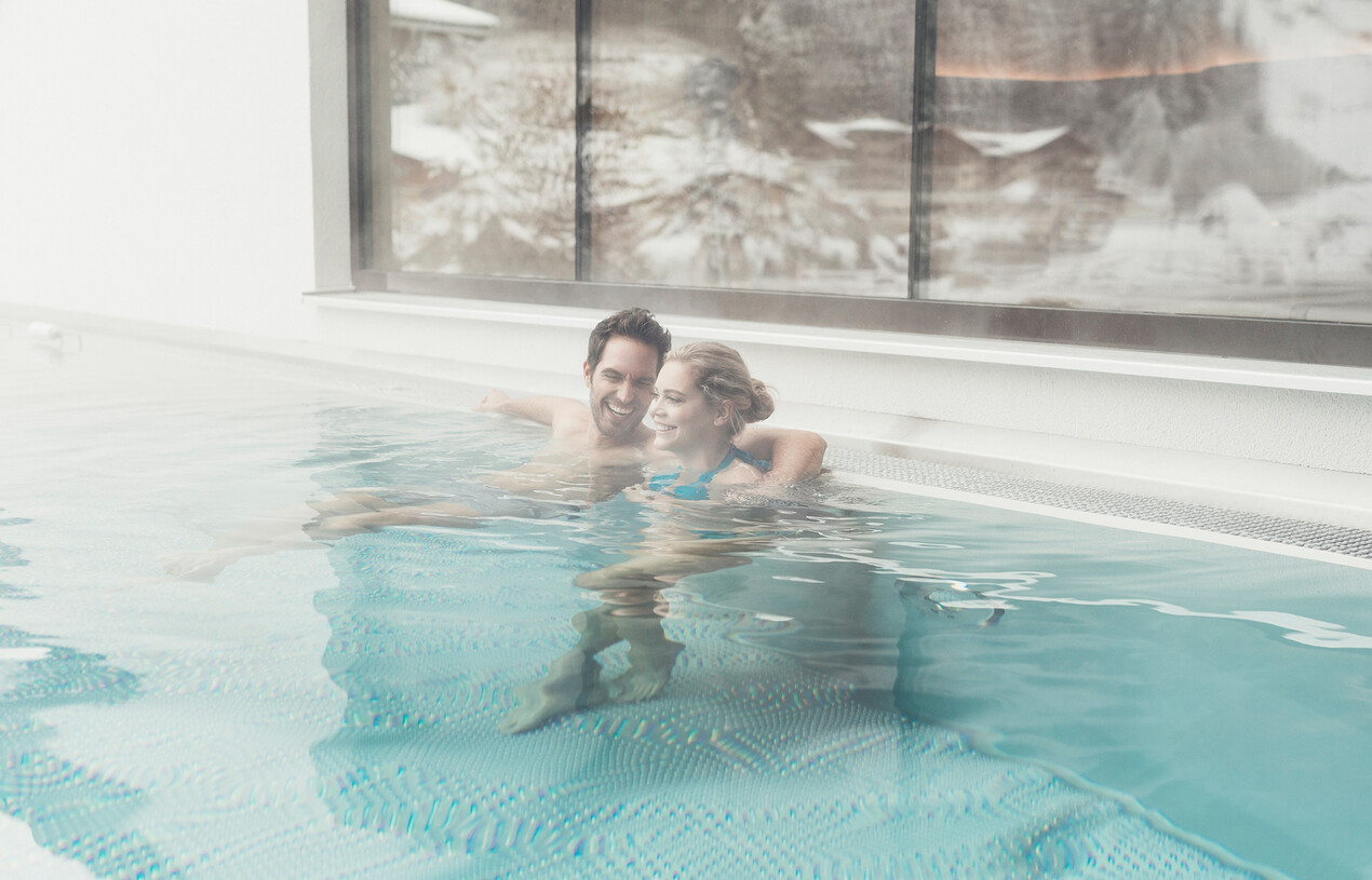 Paar im beheiztem Außenpool beim Winterurlaub im Wellnesshotel Nesslerhof in Salzburg